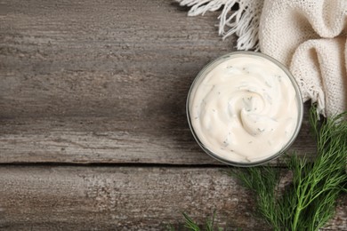 Photo of Tasty creamy sauce and fresh dill on wooden table, flat lay. Space for text