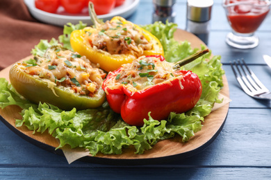 Photo of Tasty stuffed bell peppers served on blue wooden table, closeup