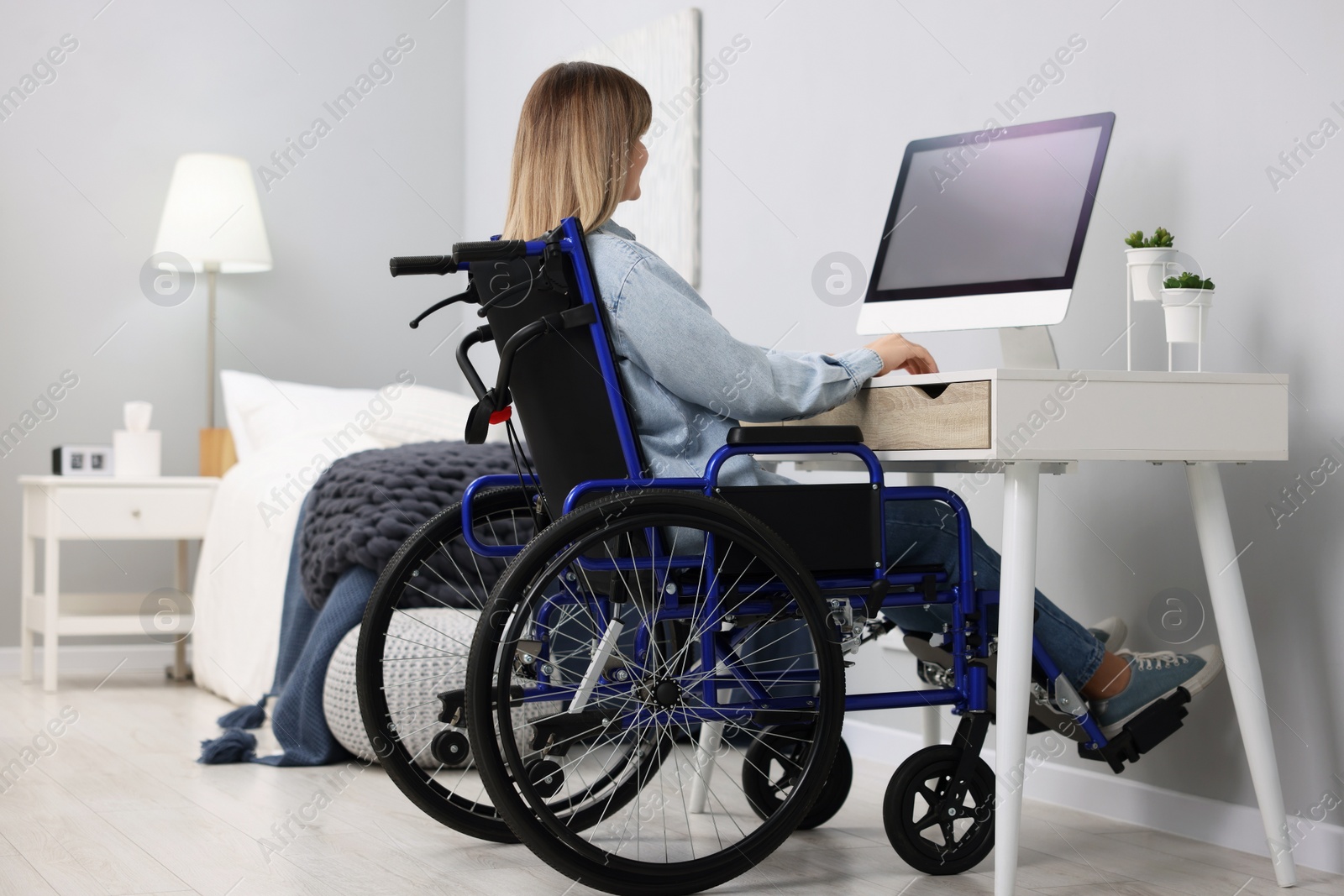 Photo of Woman in wheelchair using computer at table in home office