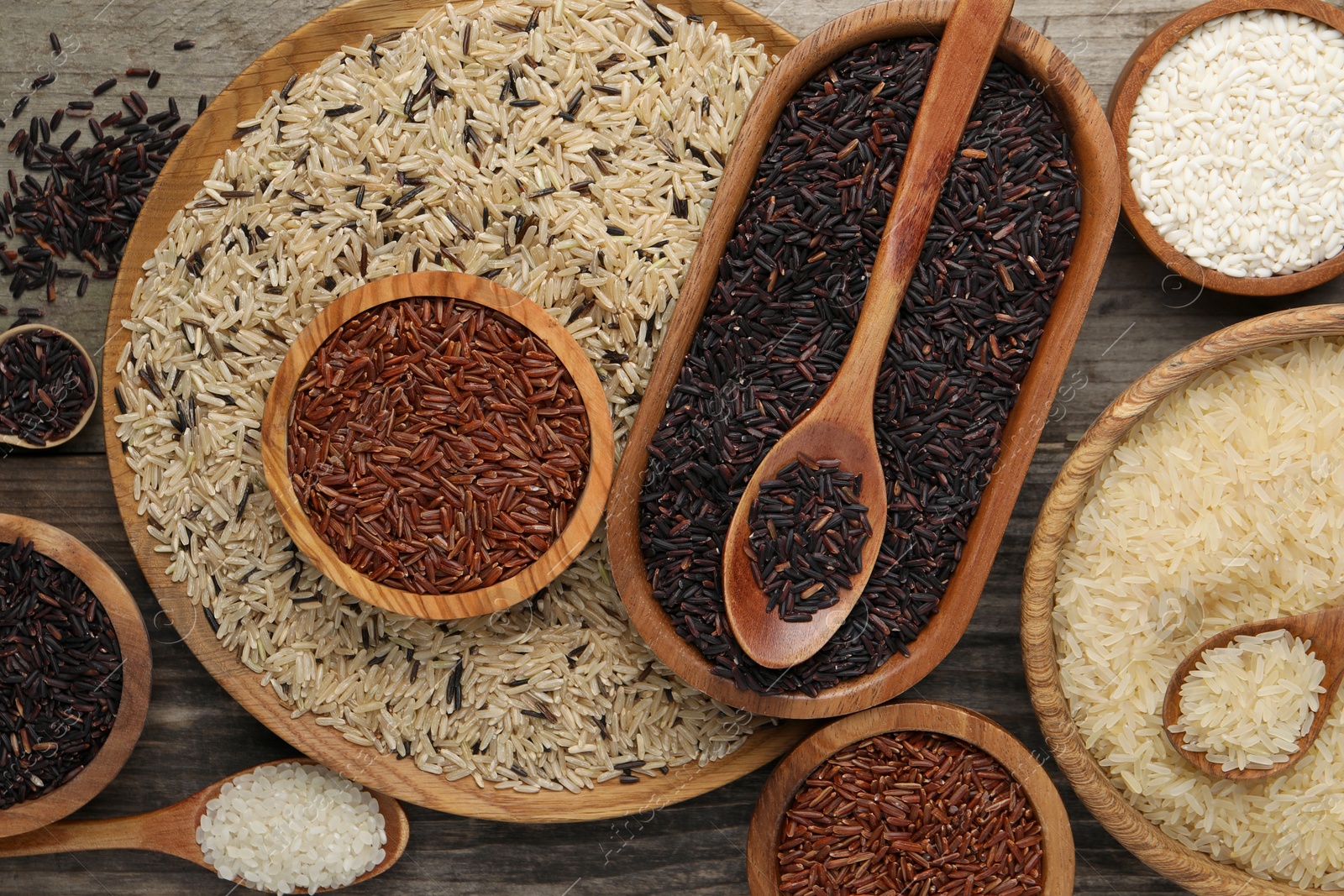 Photo of Different sorts of rice on wooden table, flat lay