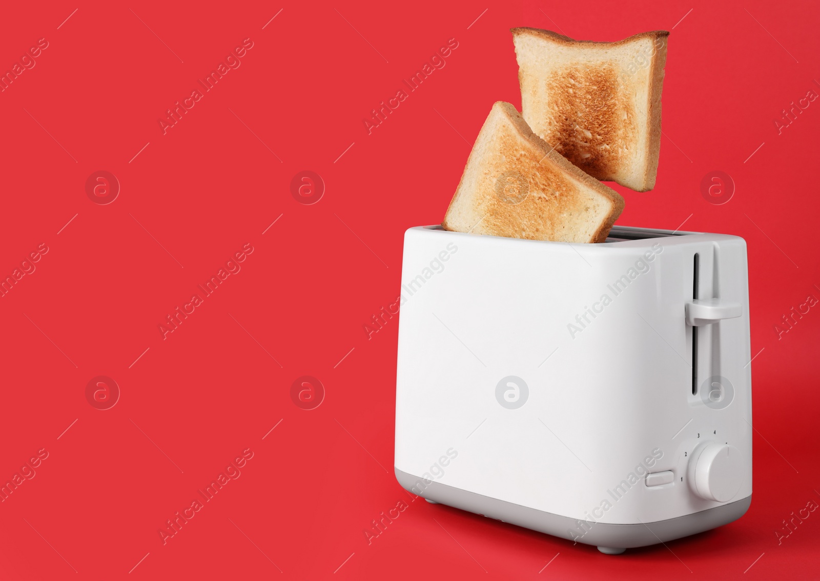 Photo of Bread slices popping up from modern toaster on red background. Space for text