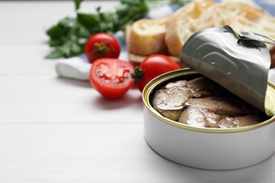 Photo of Open tin can of tasty cod liver on white wooden table, closeup. Space for text