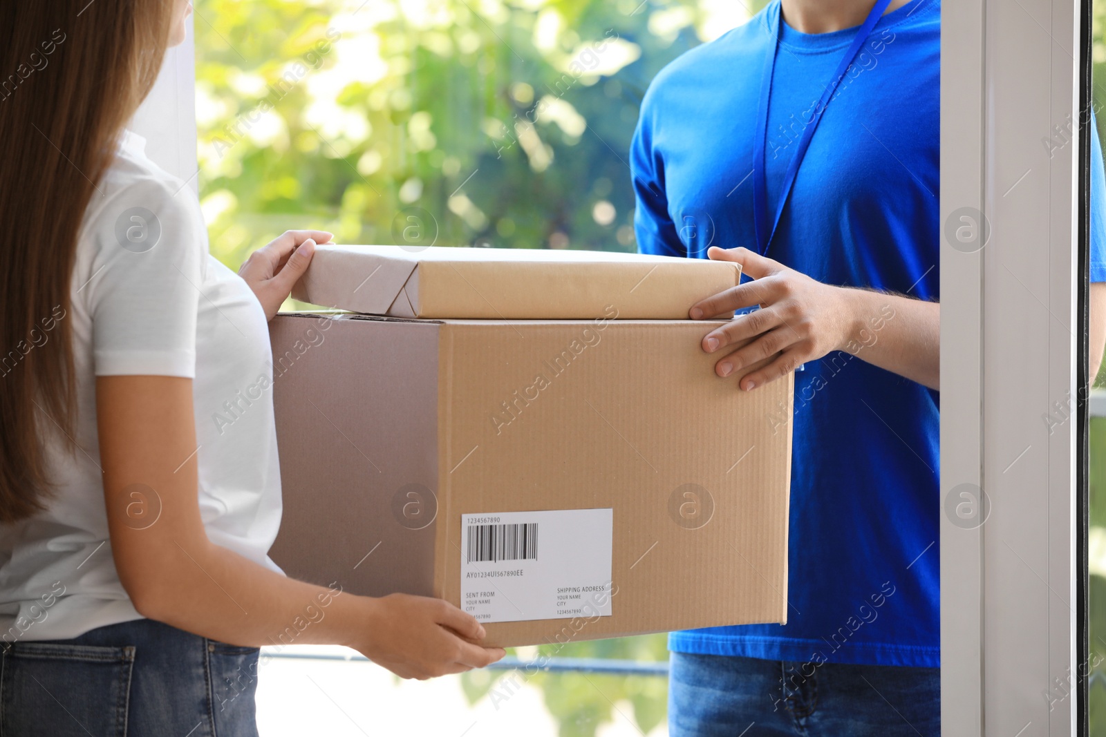 Photo of Woman receiving parcels from courier on doorstep, closeup