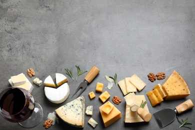 Flat lay composition with different sorts of cheese and knives on grey table. Space for text