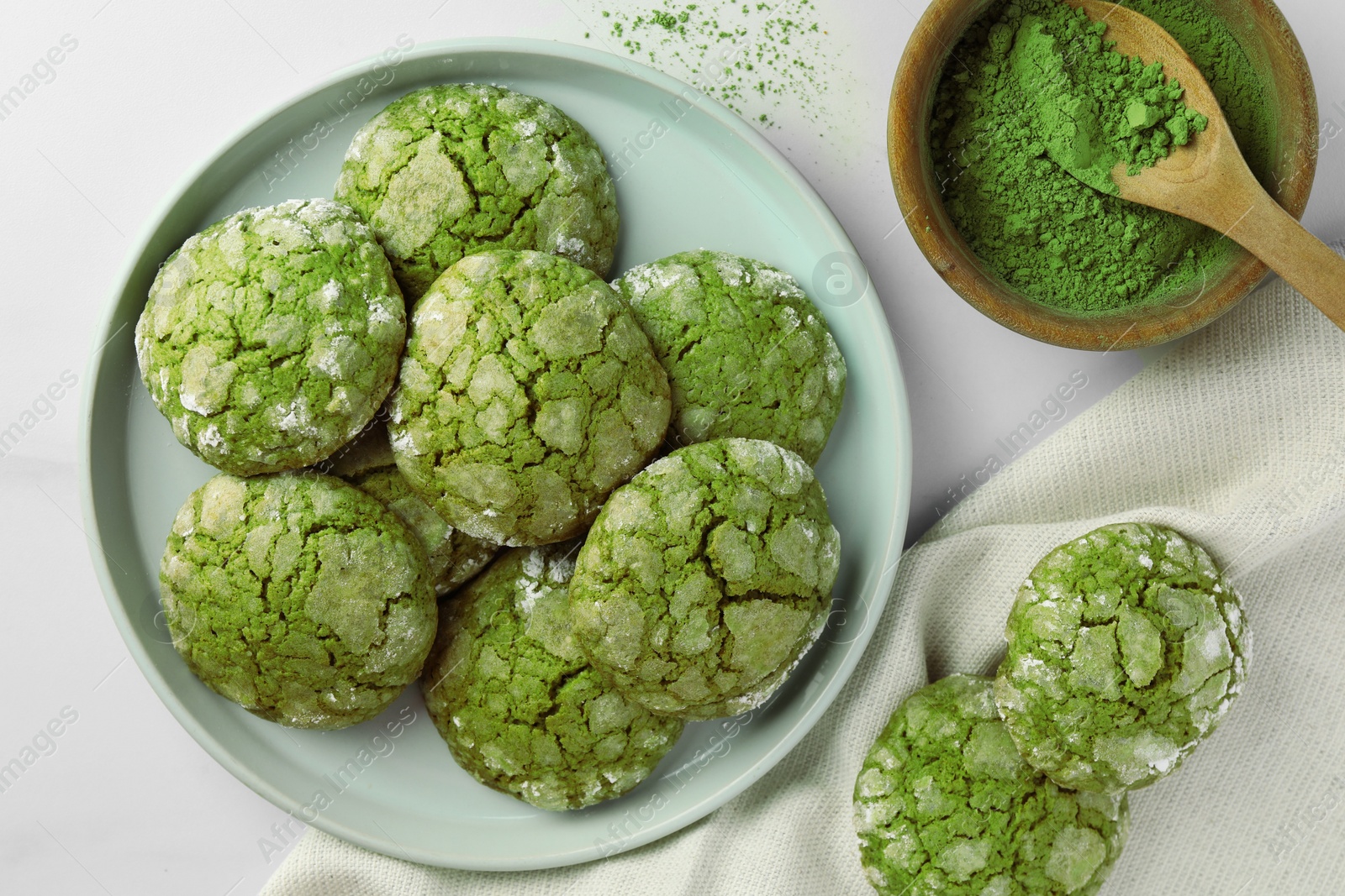 Photo of Plate with tasty matcha cookies and powder on white table, flat lay