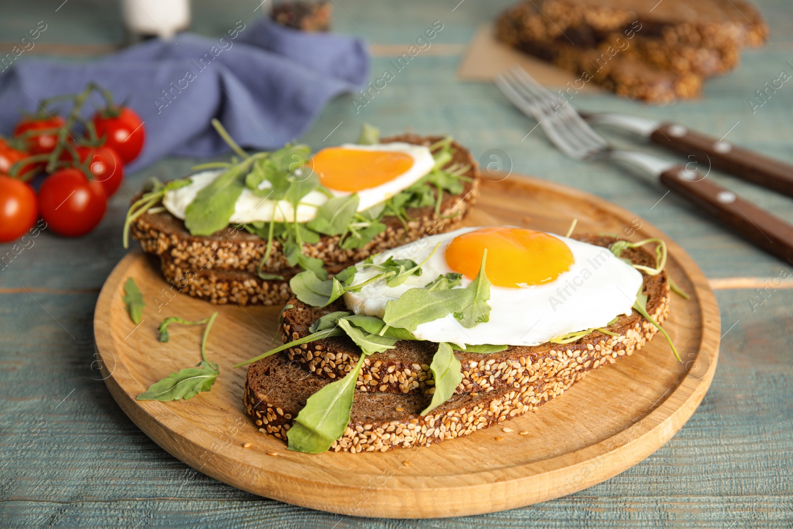 Photo of Delicious sandwiches with arugula and fried egg on blue wooden table