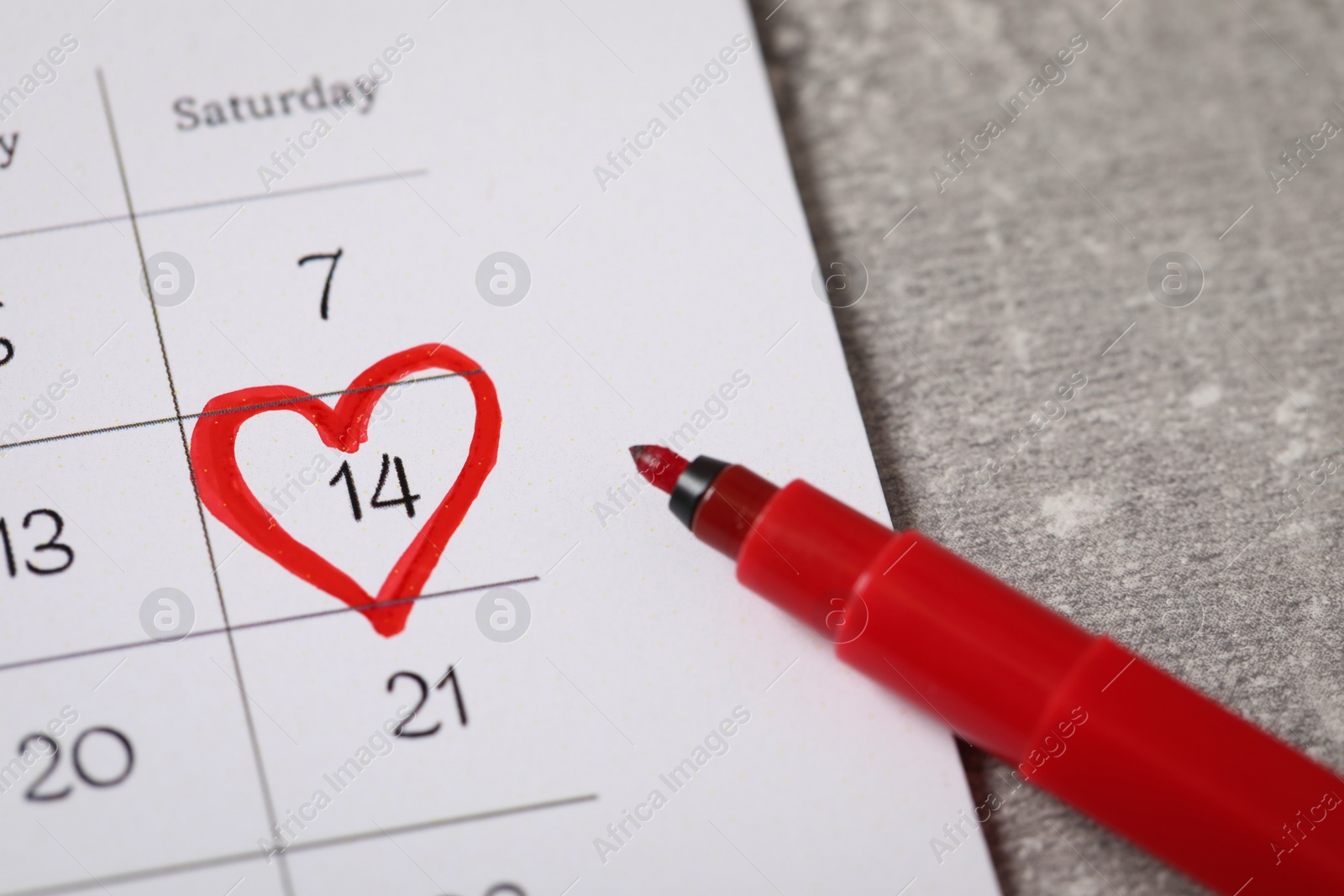 Photo of Calendar with marked Valentine's Day and red felt tip pen on grey table, closeup