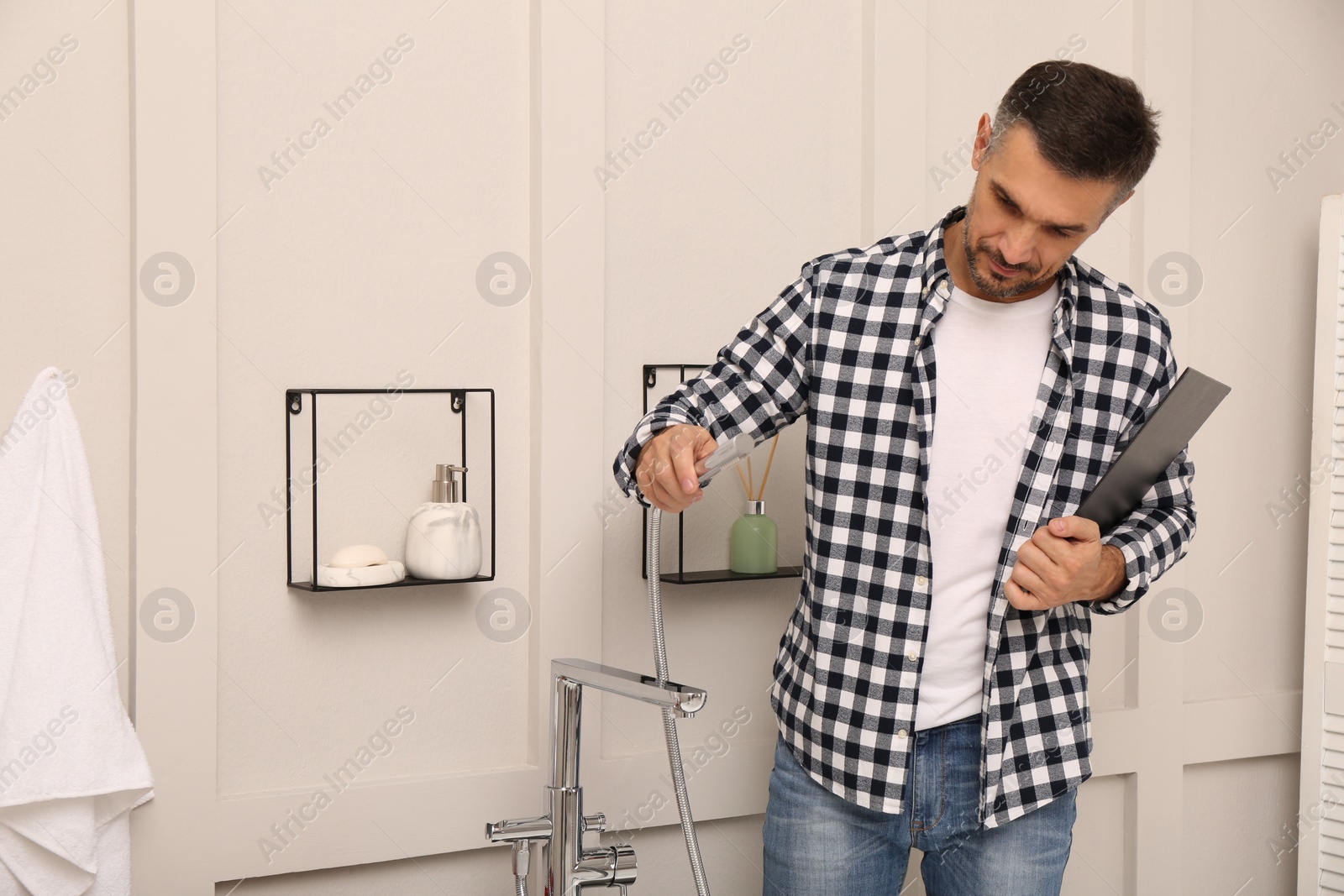 Photo of Plumber with clipboard checking water tap in bathroom