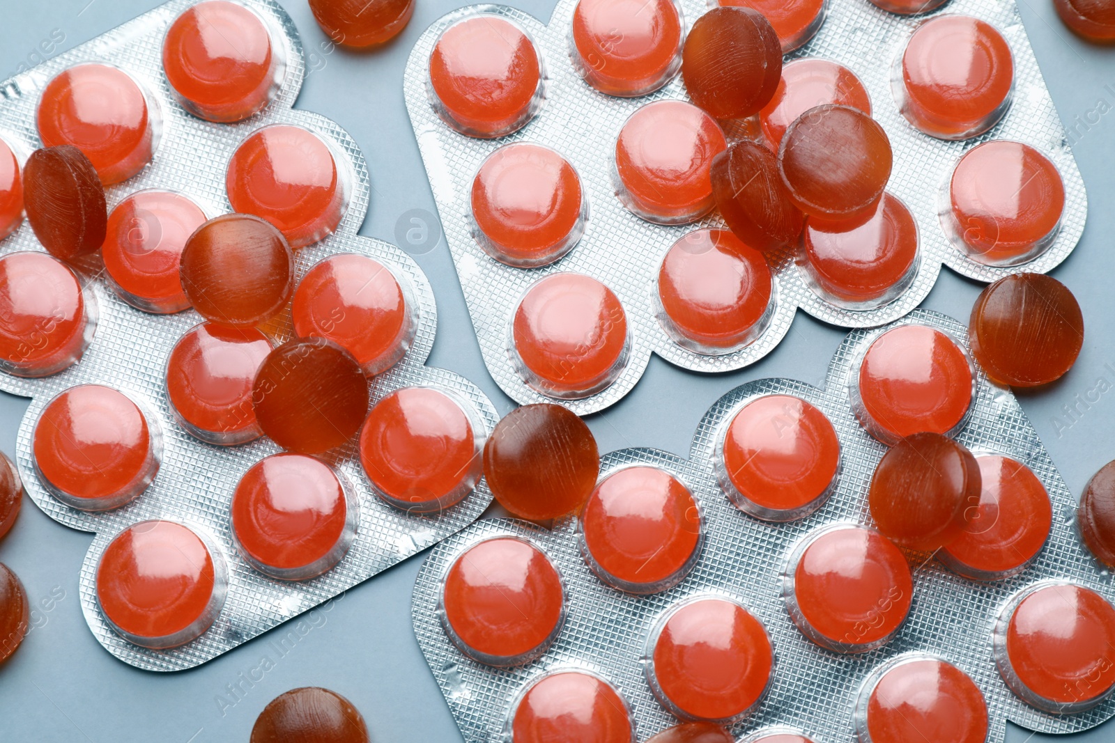 Photo of Orange cough drops on grey background, flat lay