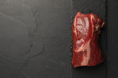 Piece of raw beef meat on black table, top view. Space for text