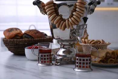 Photo of Traditional Russian samovar with treats on white table at home