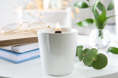 Photo of Burning candle with wooden wick on white table