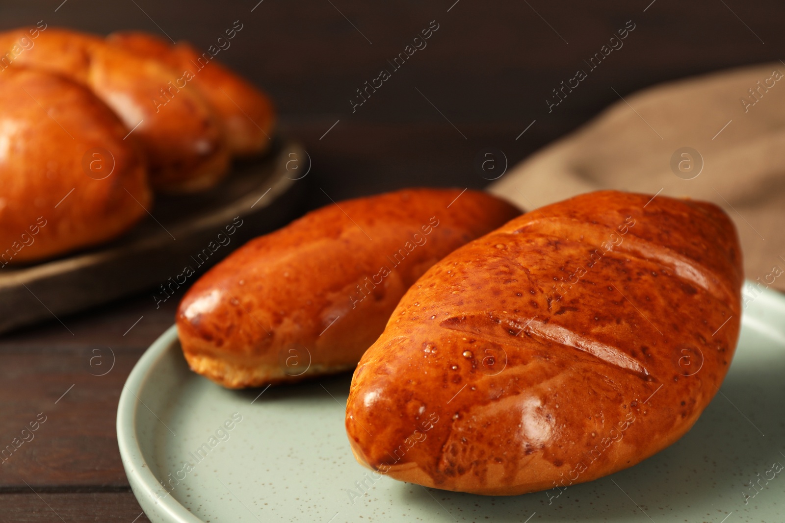 Photo of Delicious baked pirozhki on wooden table, closeup