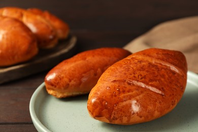 Photo of Delicious baked pirozhki on wooden table, closeup