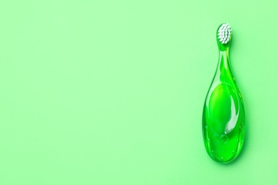 Children's toothbrush on green background, top view. Space for text