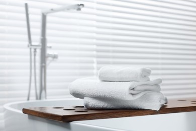 Photo of Stacked bath towels on tub tray in bathroom