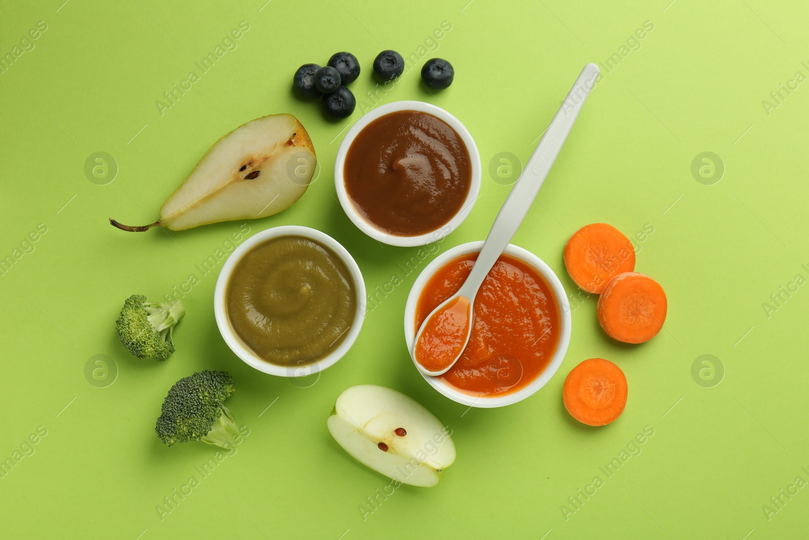 Photo of Bowls with healthy baby food, vegetables, fruits and spoon on light green background, flat lay