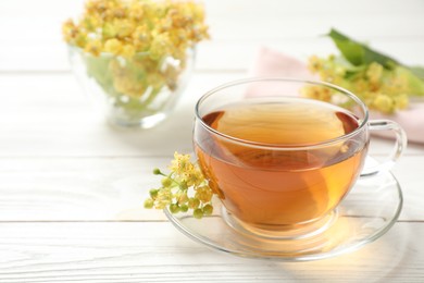 Cup of tea and linden blossom on white wooden table