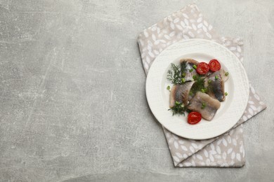 Delicious salted herring fillets served with onion, dill and cherry tomatoes on grey table, top view. Space for text