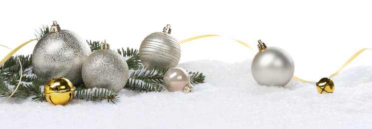Photo of Beautiful Christmas balls, fir tree branch, ribbon and sleigh bells on snow against white background