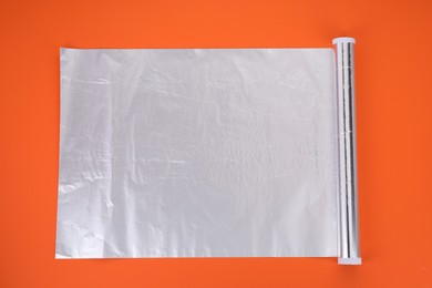 Photo of Roll of aluminum foil on orange background, top view