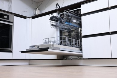 Photo of Open clean empty dishwasher in kitchen, low angle view