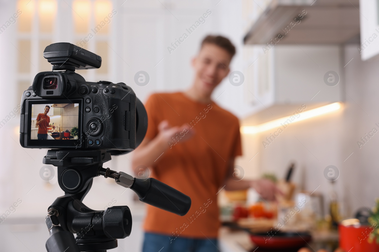 Photo of Food blogger recording video in kitchen, focus on camera