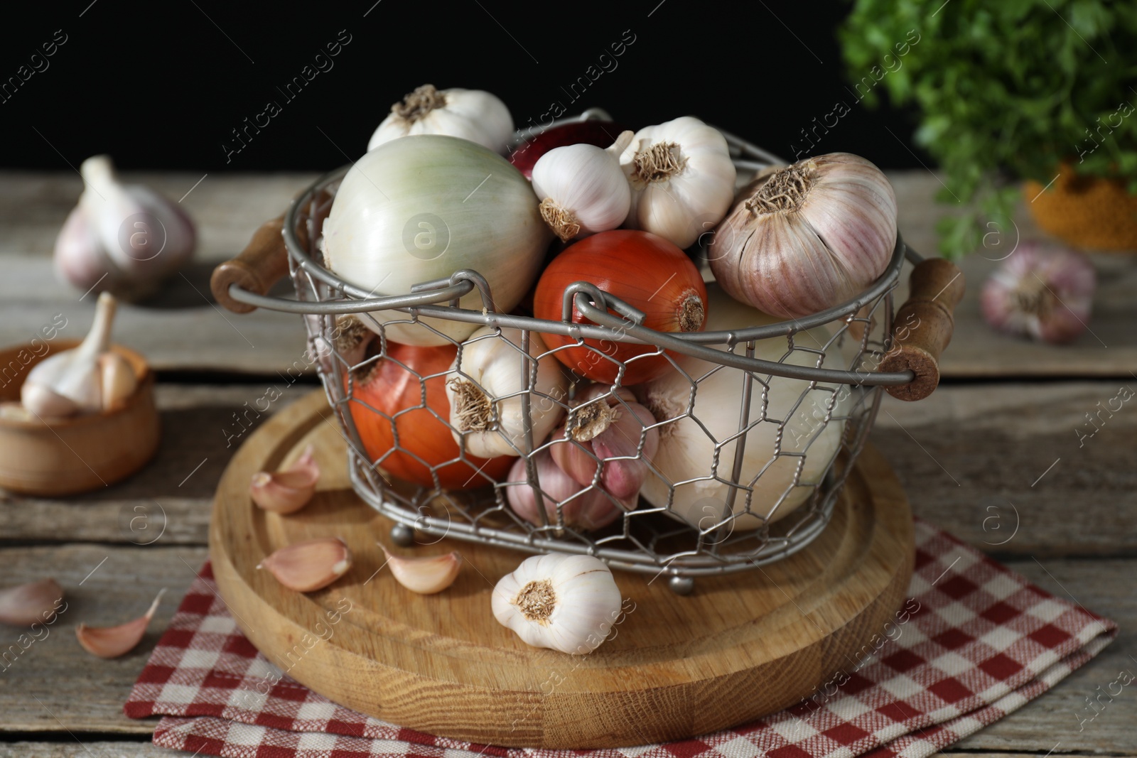 Photo of Fresh raw garlic and onions in metal basket on table, closeup