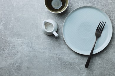 Photo of Stylish empty dishware and fork on light grey table, flat lay. Space for text
