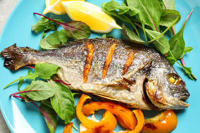 Photo of Delicious roasted fish with lemon and vegetables on plate, closeup view