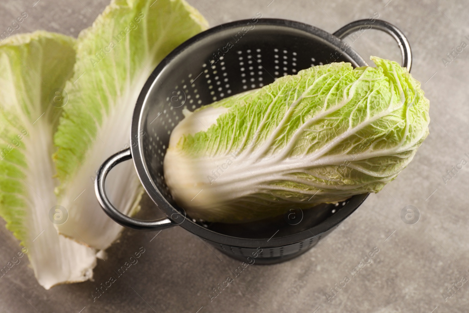 Photo of Fresh ripe Chinese cabbage and leaves on light grey table