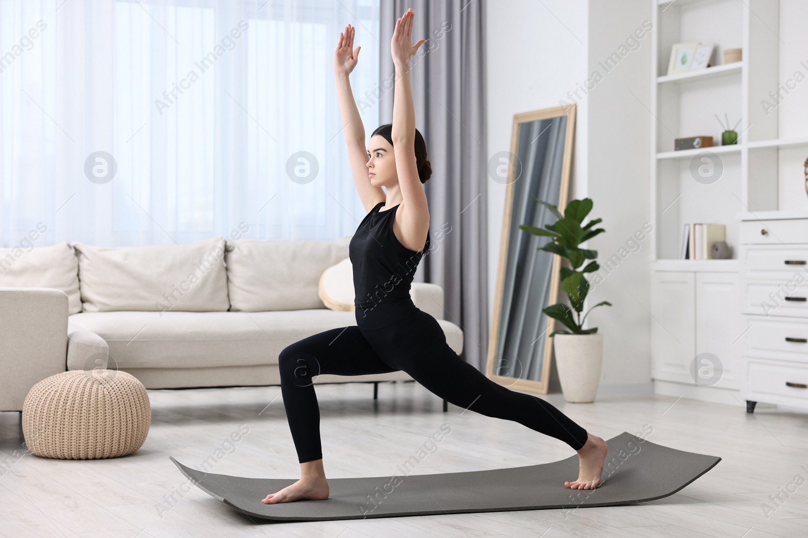 Photo of Girl practicing crescent asana on yoga mat at home. High lunge pose