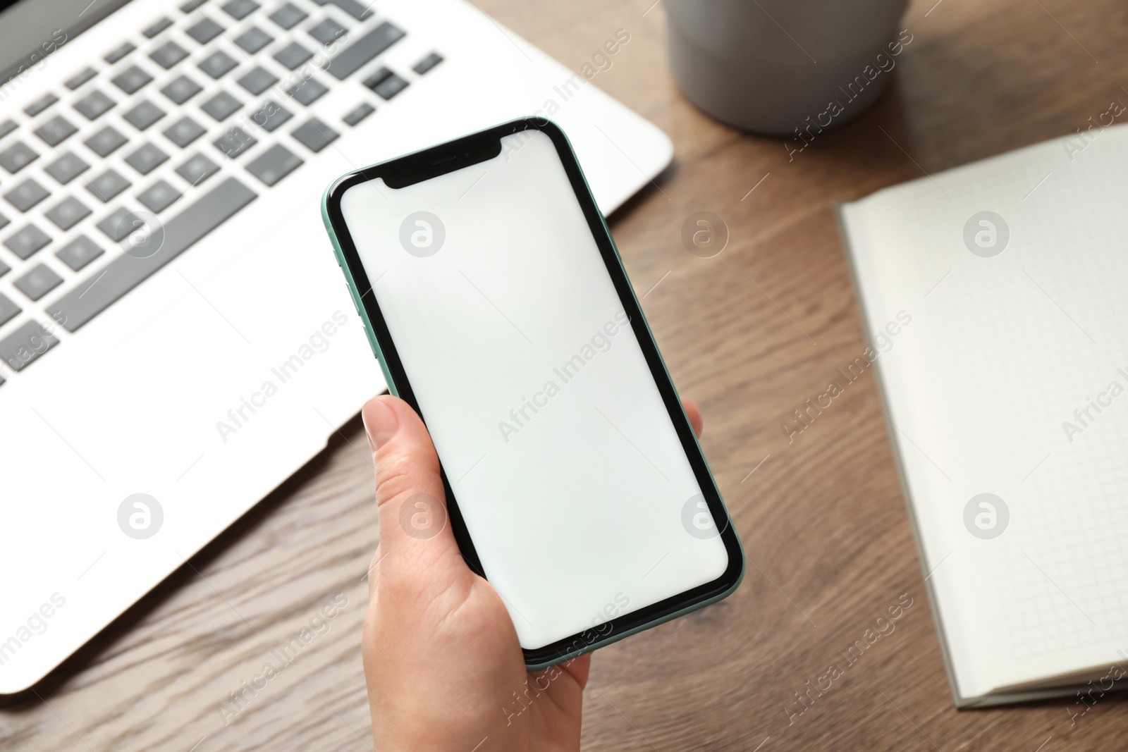 Photo of MYKOLAIV, UKRAINE - JULY 8, 2020: Woman holding Iphone 11 Pro Max with blank screen at workplace, closeup