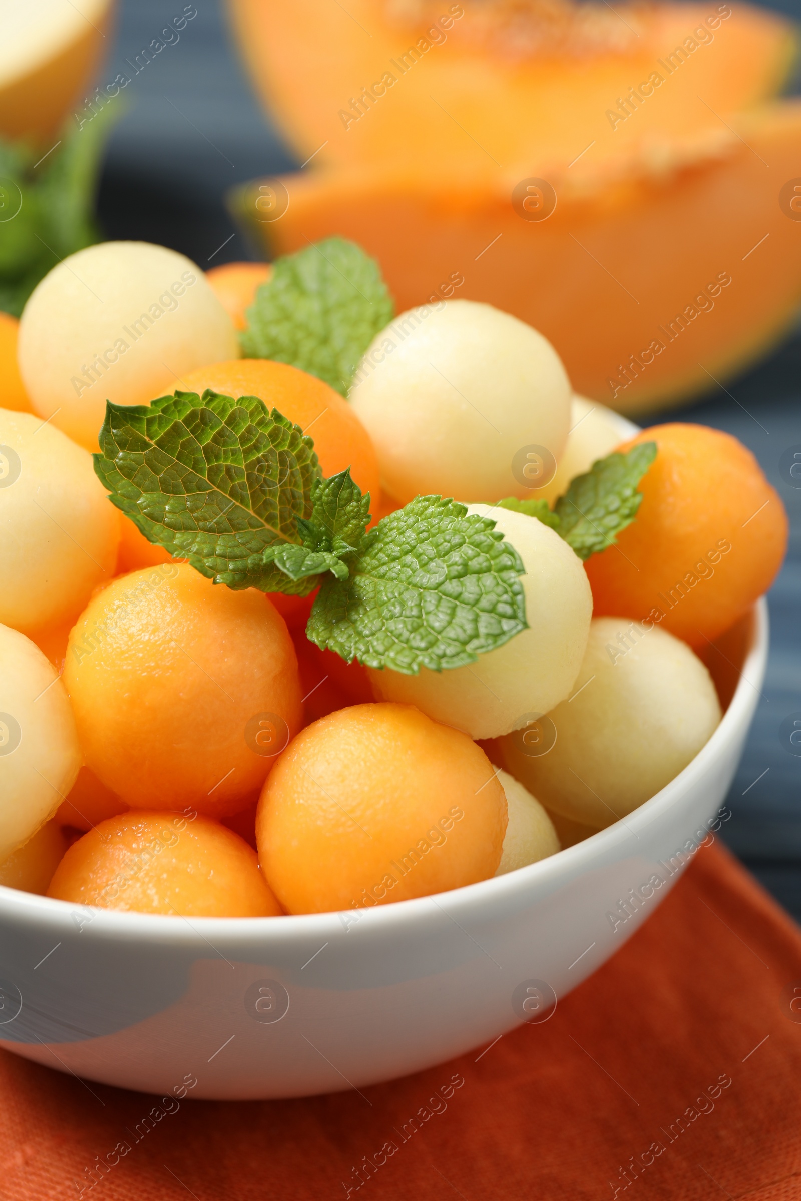 Photo of Melon balls and mint in bowl on table, closeup