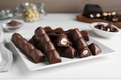 Photo of Tasty chocolate bars with nuts on white wooden table