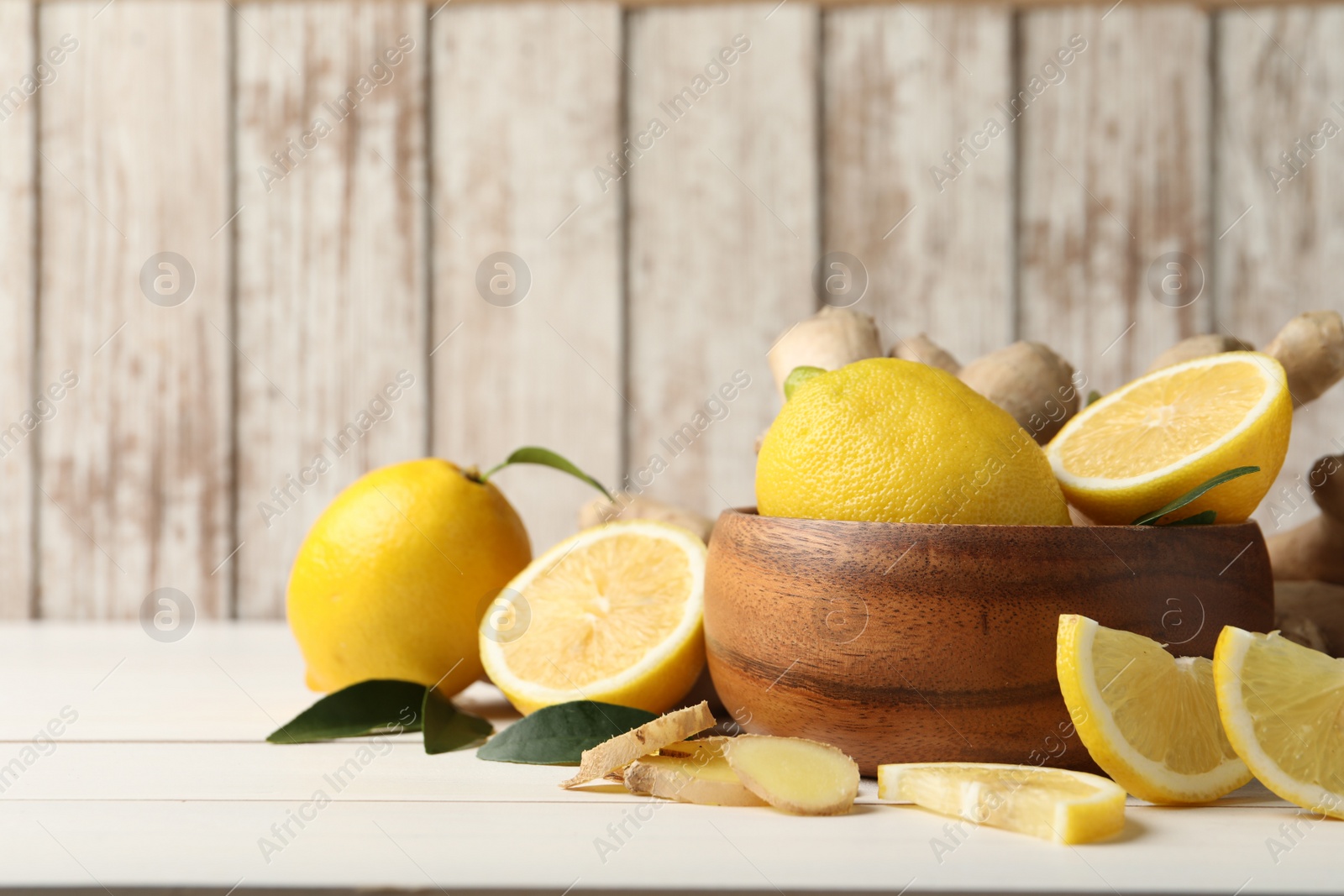 Photo of Fresh lemons and ginger on white wooden table