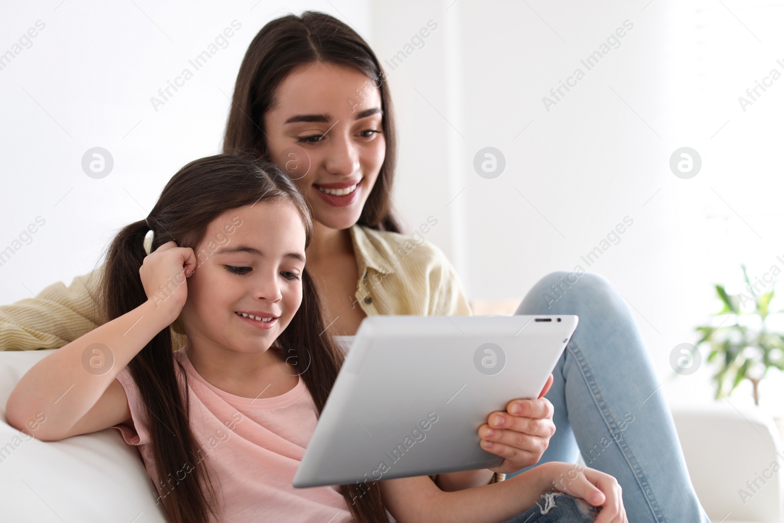 Photo of Mother and daughter reading E-book together at home