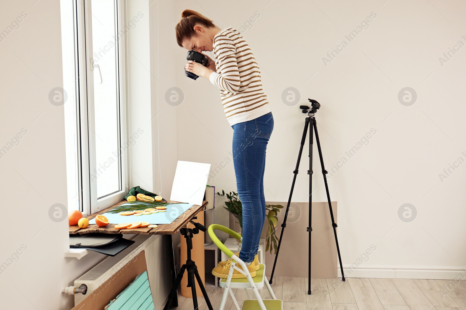 Photo of Woman taking picture of cut fruits and palm leaf on window sill. Food photography