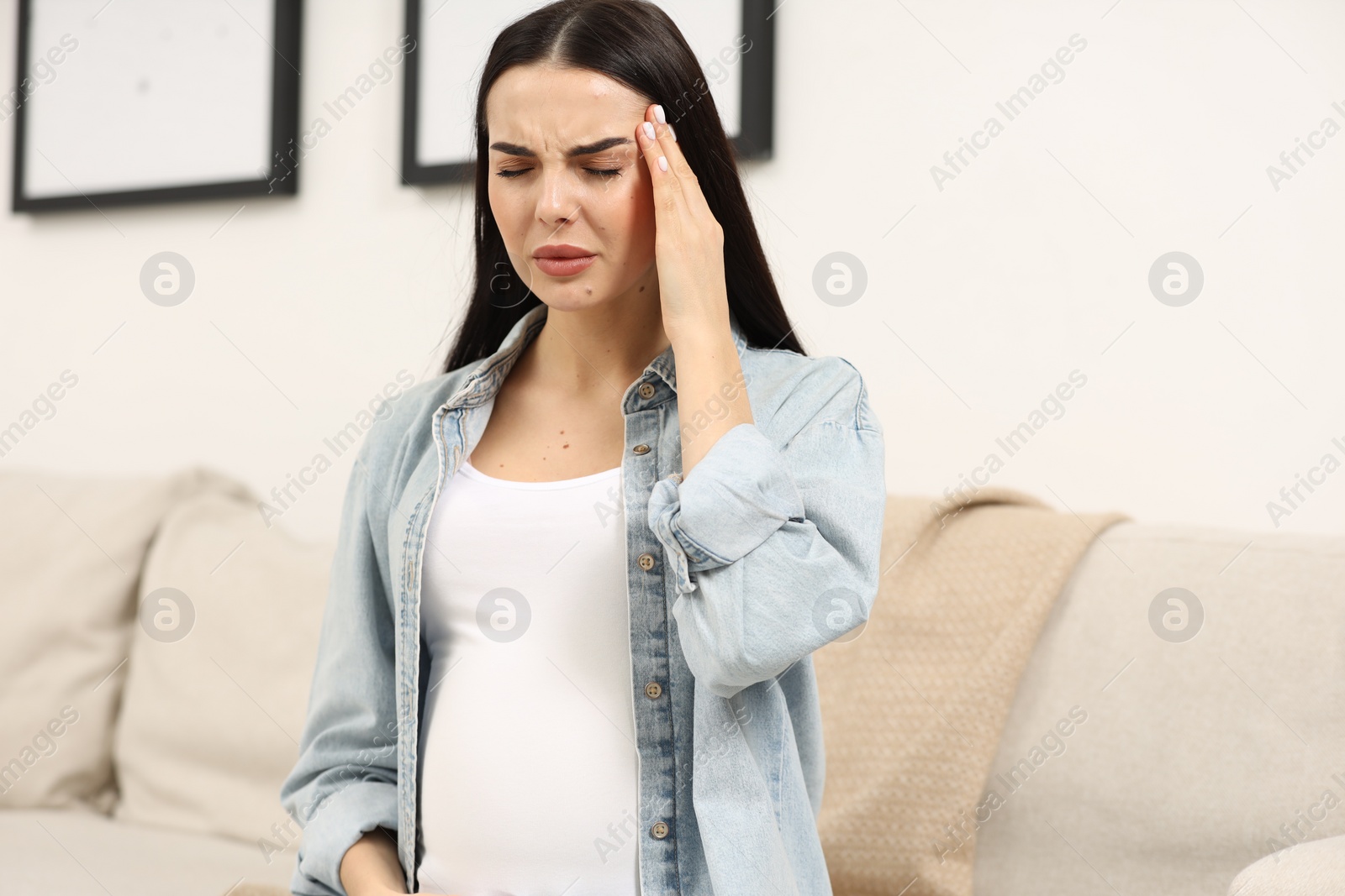 Photo of Pregnant young woman suffering from headache indoors