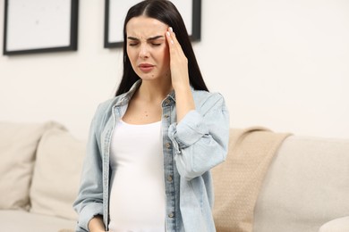 Pregnant young woman suffering from headache indoors