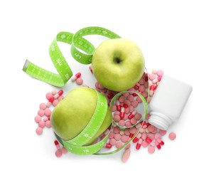 Weight loss pills, apples and measuring tape on white background, top view