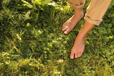 Photo of Woman walking barefoot on green grass outdoors, above view. Space for text