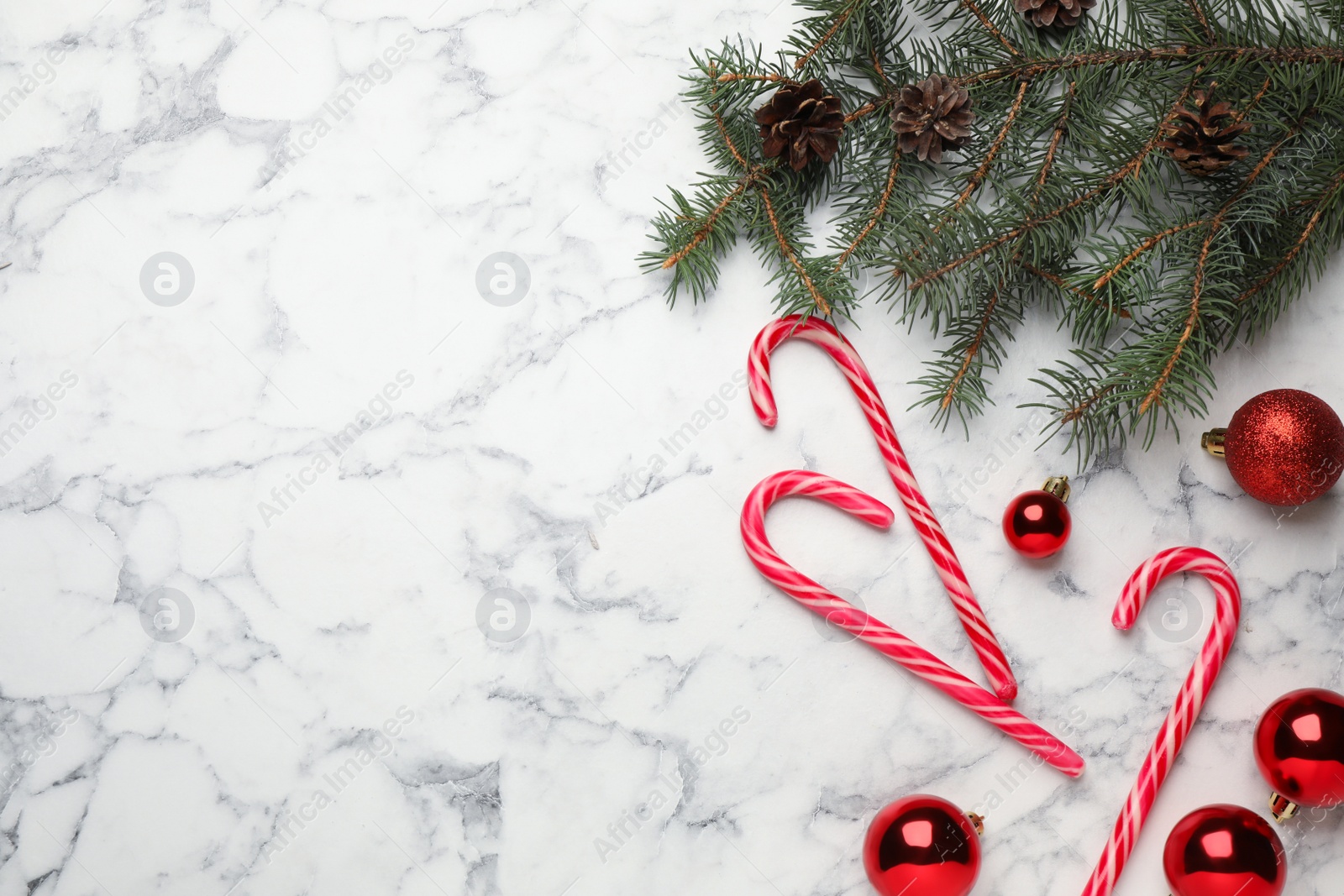 Photo of Tasty candy canes and Christmas decor on white marble table, flat lay. Space for text