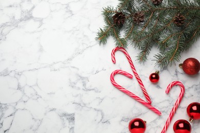 Tasty candy canes and Christmas decor on white marble table, flat lay. Space for text