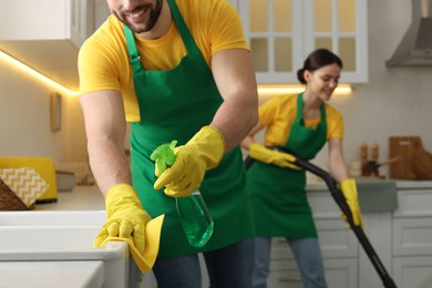 Photo of Professional janitors working in kitchen, closeup. Cleaning service