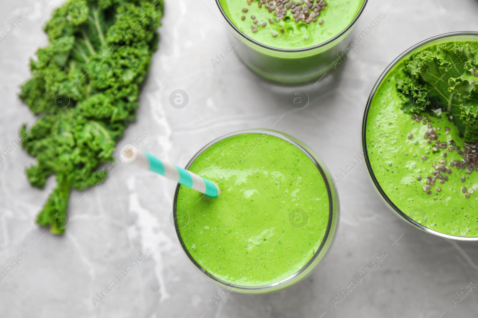 Photo of Tasty kale smoothie on light grey marble table, flat lay