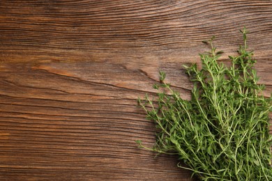 Bunch of aromatic thyme on wooden table, top view. Space for text