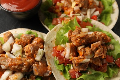 Photo of Delicious tacos with vegetables and meat on table, closeup