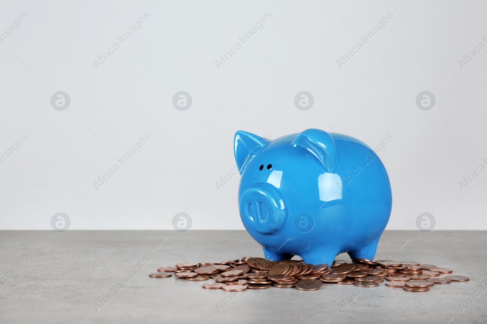 Photo of Piggy bank and coins on table against white background. Space for text