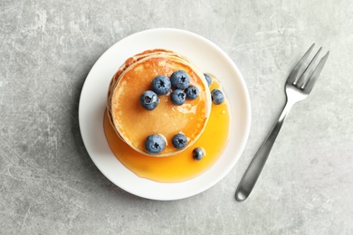 Plate with pancakes and berries on grey background, top view